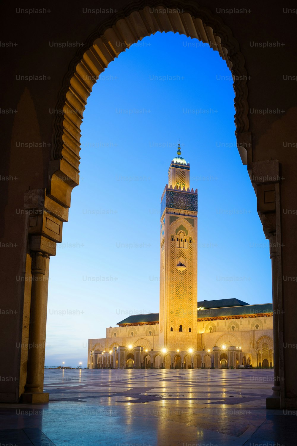 The illuminated Hassan II Mosque with its reflection on the stoned ground in Casablanca, Morocco
