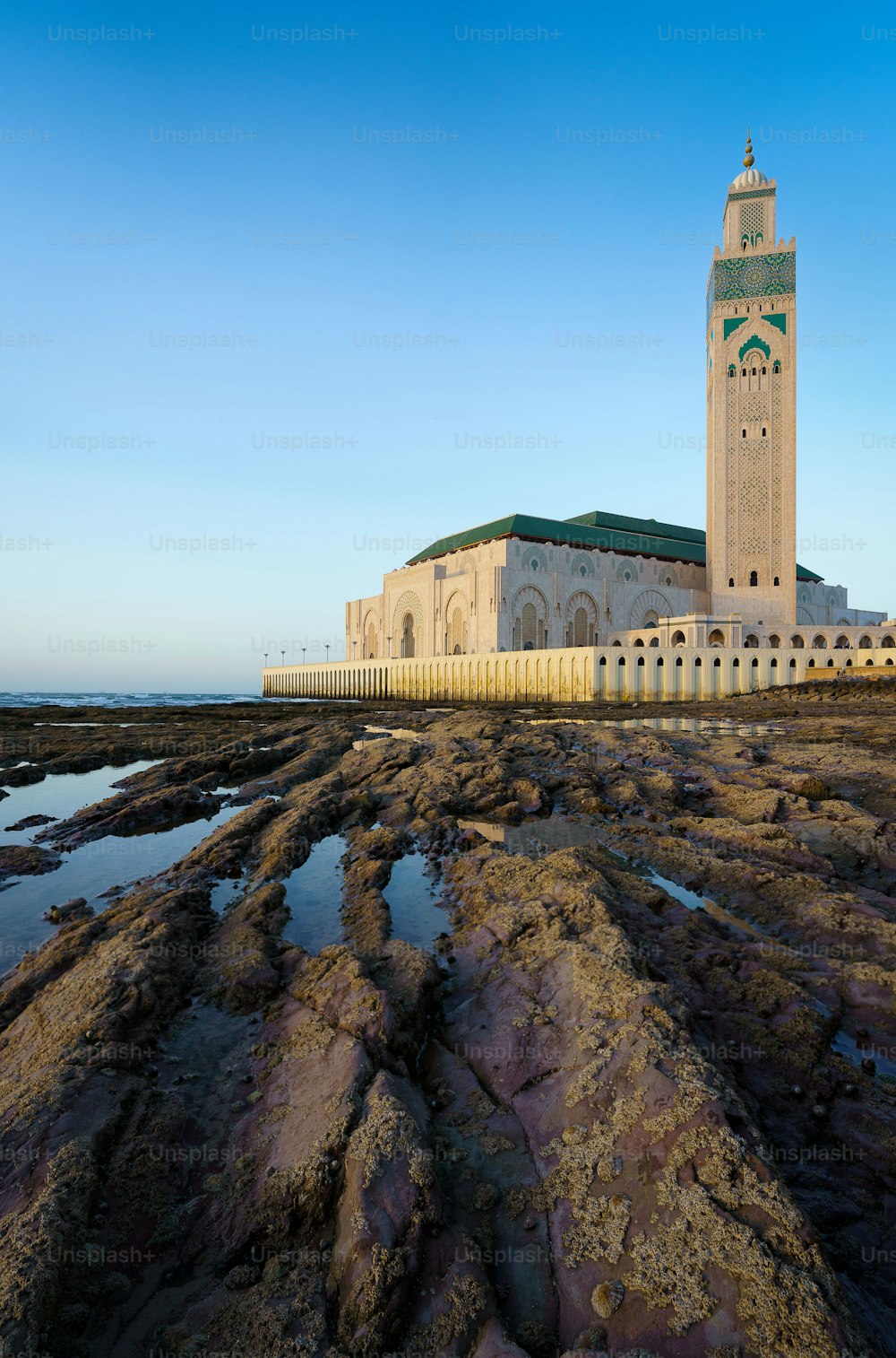 The beautiful Hassan II Mosque with rocks and water in the foreground in Casablanca, Morocco