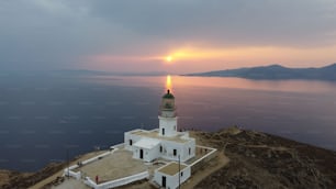 Vista fascinante del hermoso paisaje marino con el faro de Armenistis en la orilla del mar en la puesta de sol escénica en Grecia