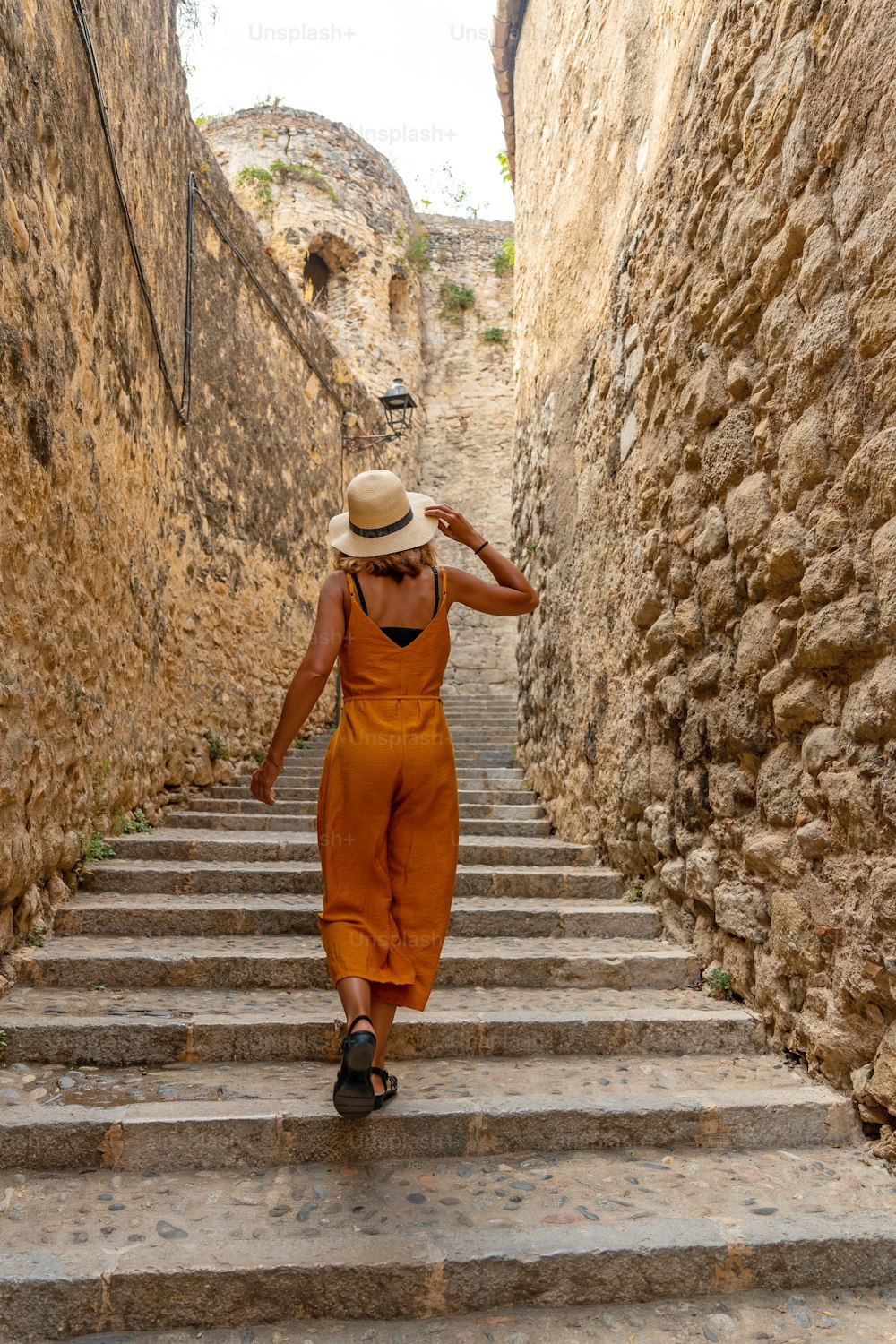Girona medieval city, a young tourist with a hat on the stairs of the streets of the historic center, Costa Brava of Catalonia in the Mediterranean. Spain