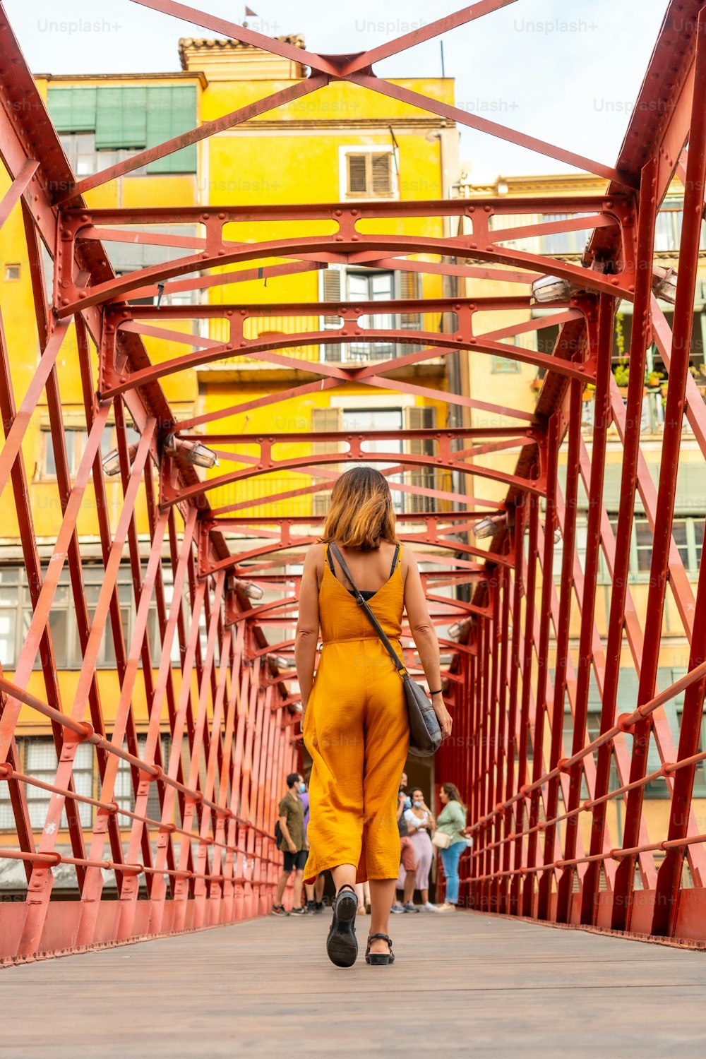 Girona ciudad medieval, un joven turista naranja en el famoso puente rojo Pont de les Peixateries Velles, Costa Brava de Cataluña