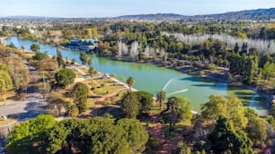 An aerial view of the lake and trees in Parque General San Martin under the blue sky