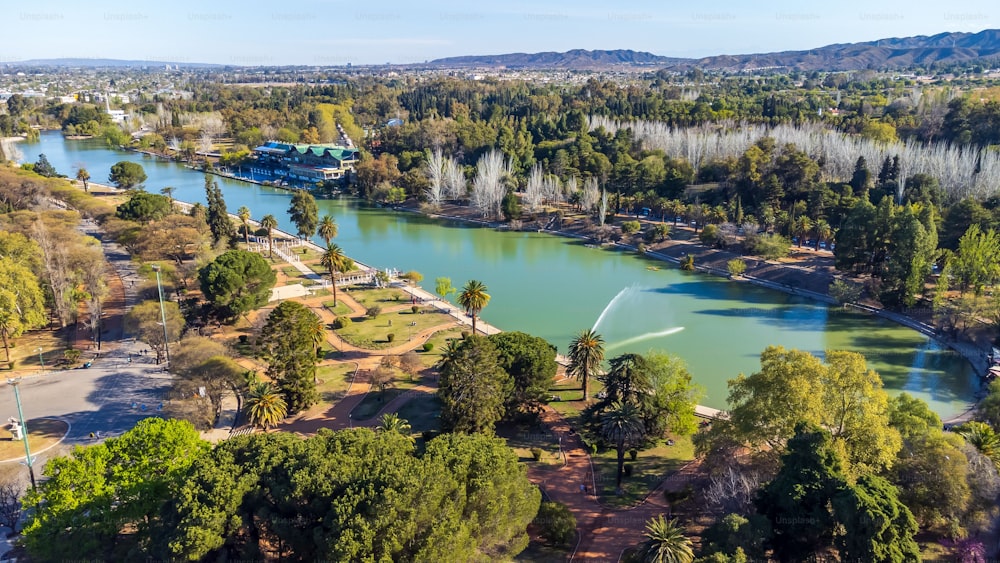 An aerial view of the lake and trees in Parque General San Martin under the blue sky