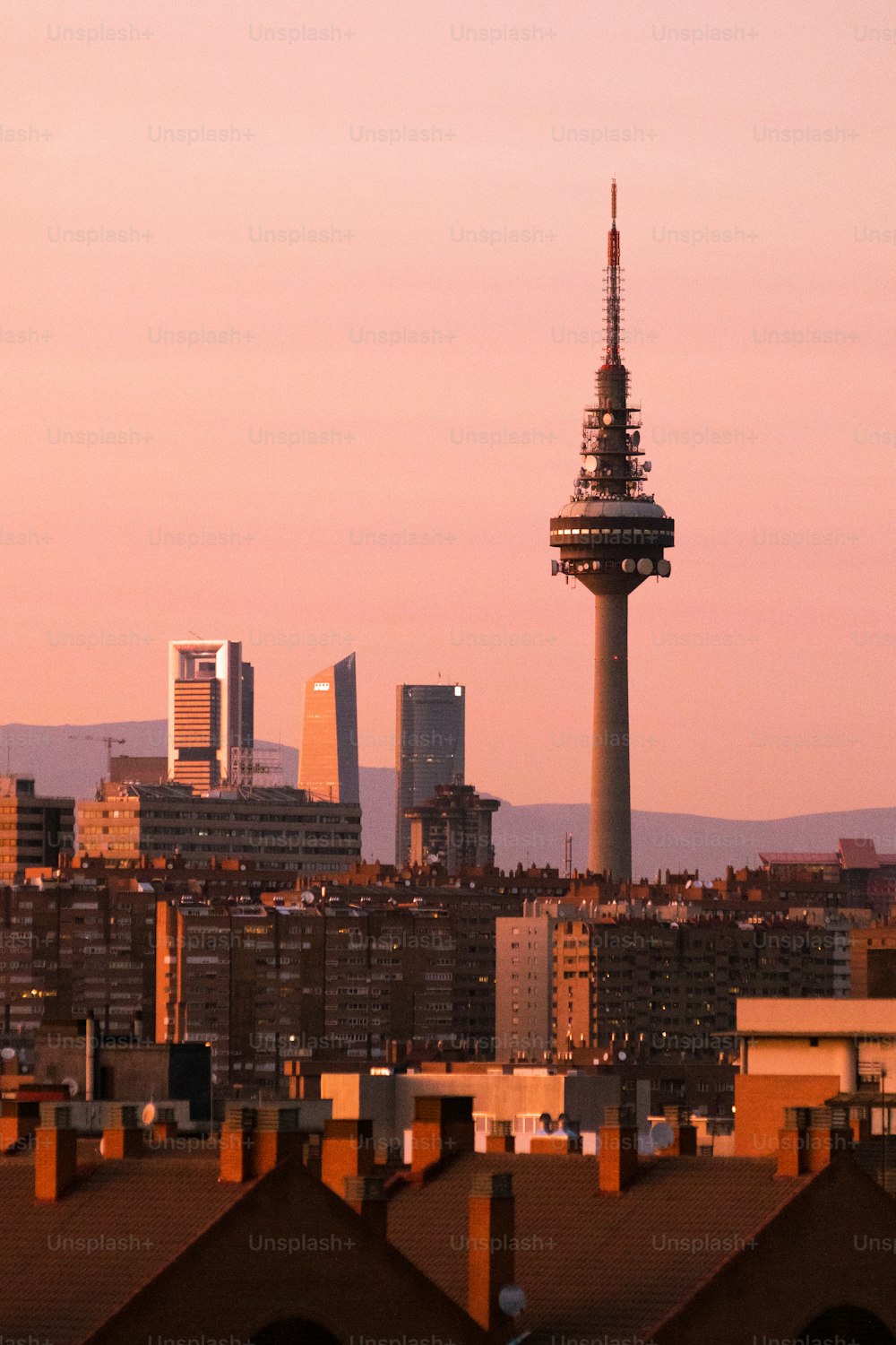 A fantastic vertical cityscape of Madrid with sunlit modern high-rise buildings and TV tower at twilight
