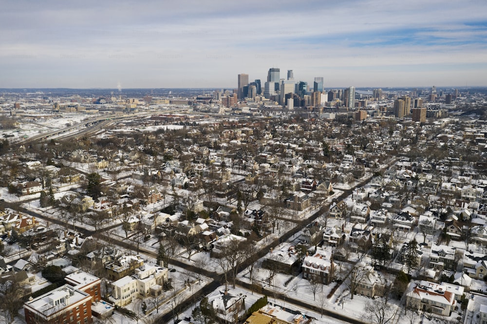 Aerial drone imagery of Minneapolis, Minnesota skyline viewed through a residential neighborhood on a partly cloudy day.