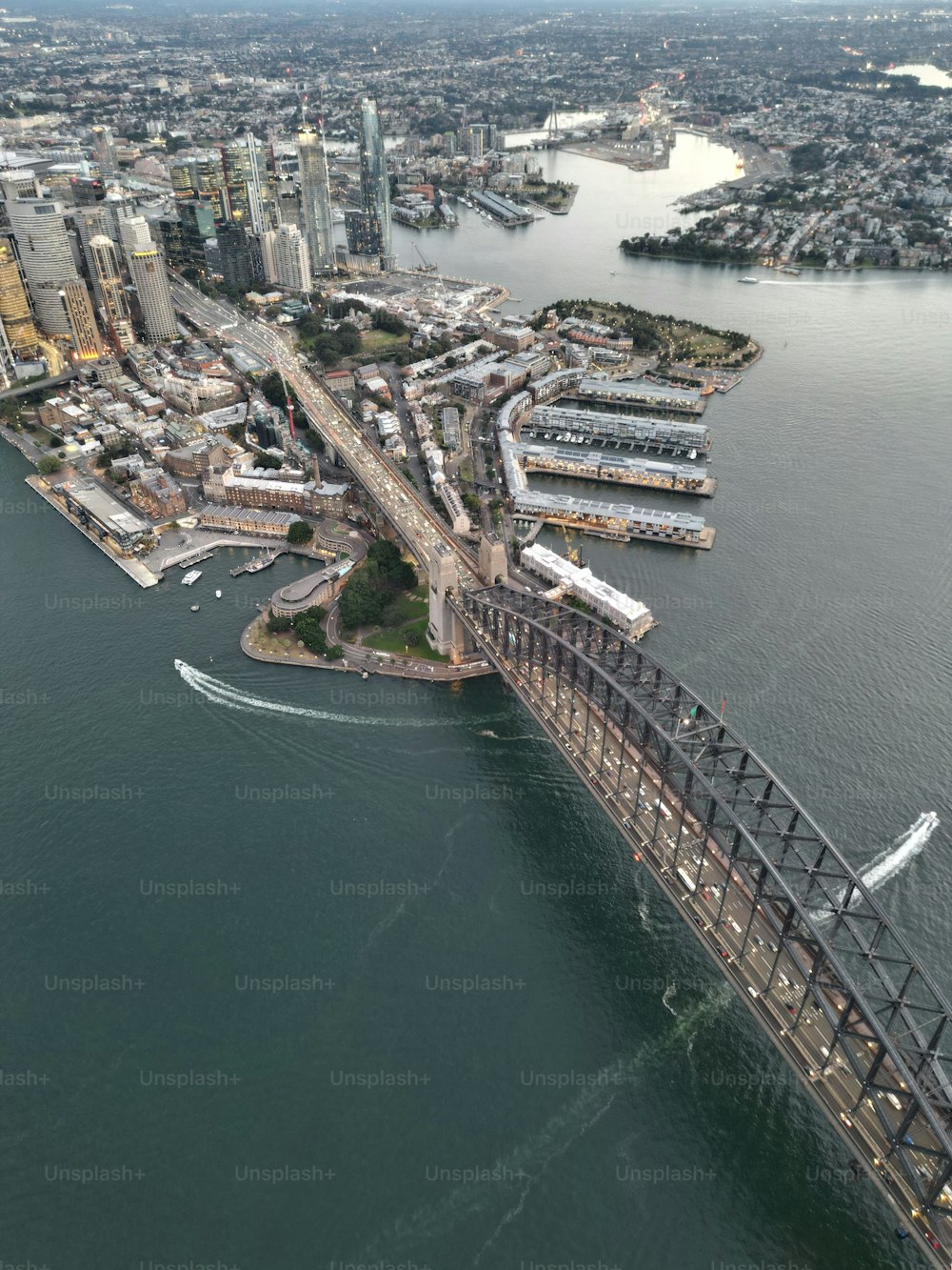 A vertical aerial view of the Sydney harbor bridge and a surrounding cityscape