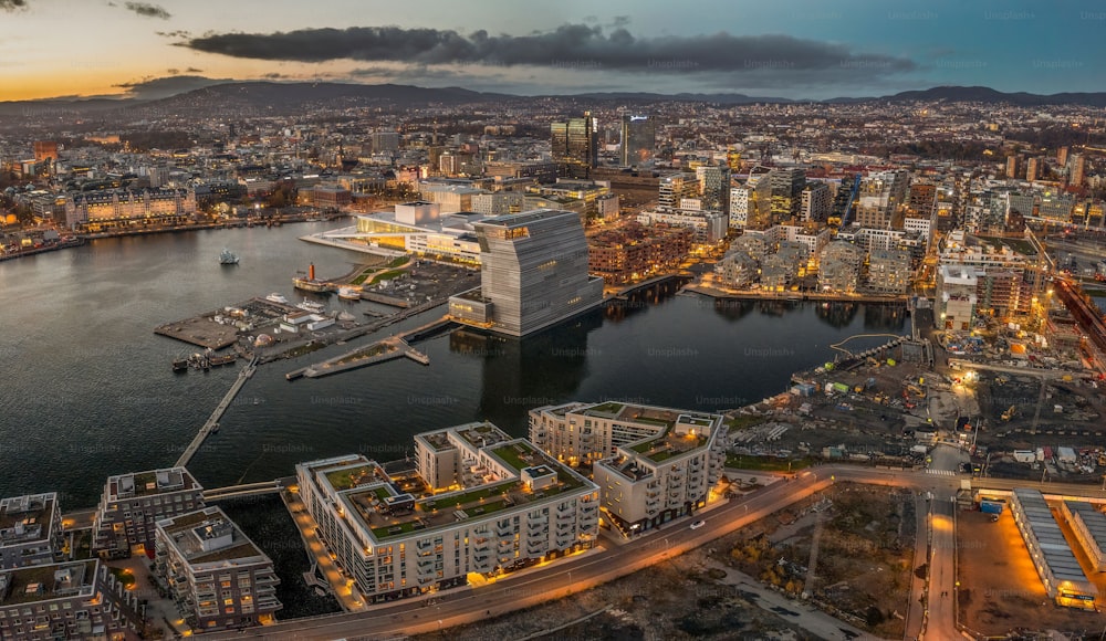 Uma foto aérea de Oslo ao pôr do sol, com muitos edifícios e luzes, cercada pelo mar, Noruega