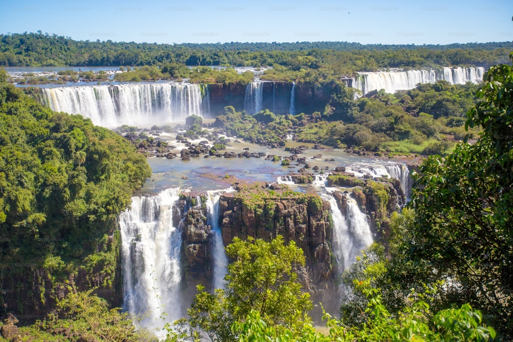 The Iguazu Falls in Brazil surrounded by trees under the blue sky