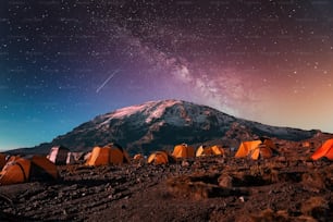 Um acampamento no fundo da montanha Kilimanjaro sob a Via Láctea