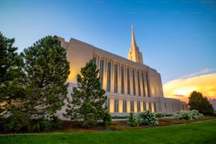 A mormon church in Utah at the sunset in a beautiful park with green grass and trees