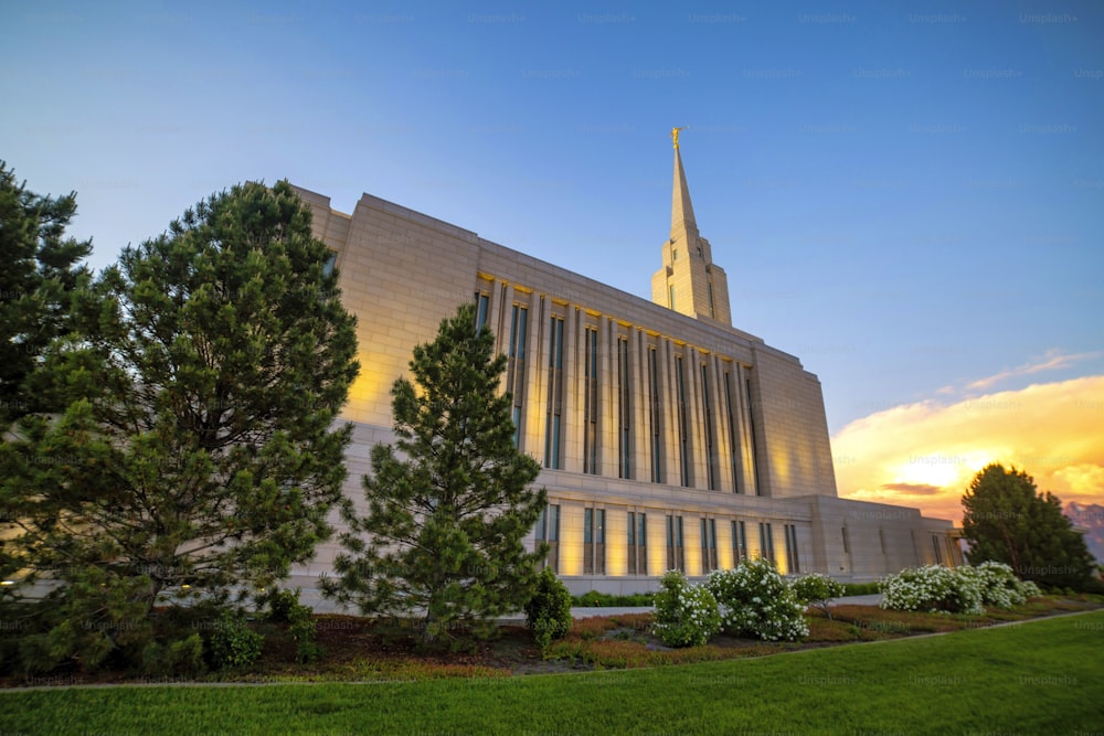 A mormon church in Utah at the sunset in a beautiful park with green grass and trees