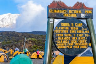 Uma foto de ângulo baixo de uma placa na entrada do Parque Nacional Kilimanjaro, na Tanzânia