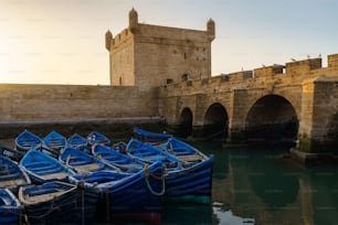 Alguns barcos de pato azul no porto de Essaouira Skala Du Port com um horizonte bonito