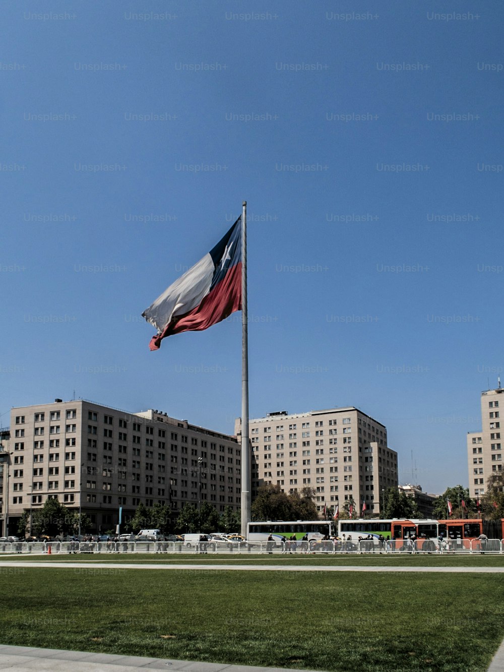 Une prise de vue verticale d’un drapeau chilien sur la place de la Constitution au Chili avec un ciel bleu clair en arrière-plan