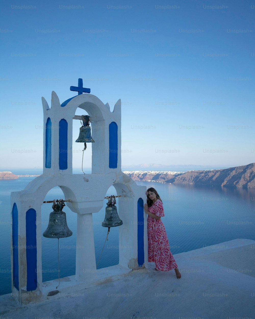 A vertical shot of a girl posing near the bells with a sea in background in Cyprus