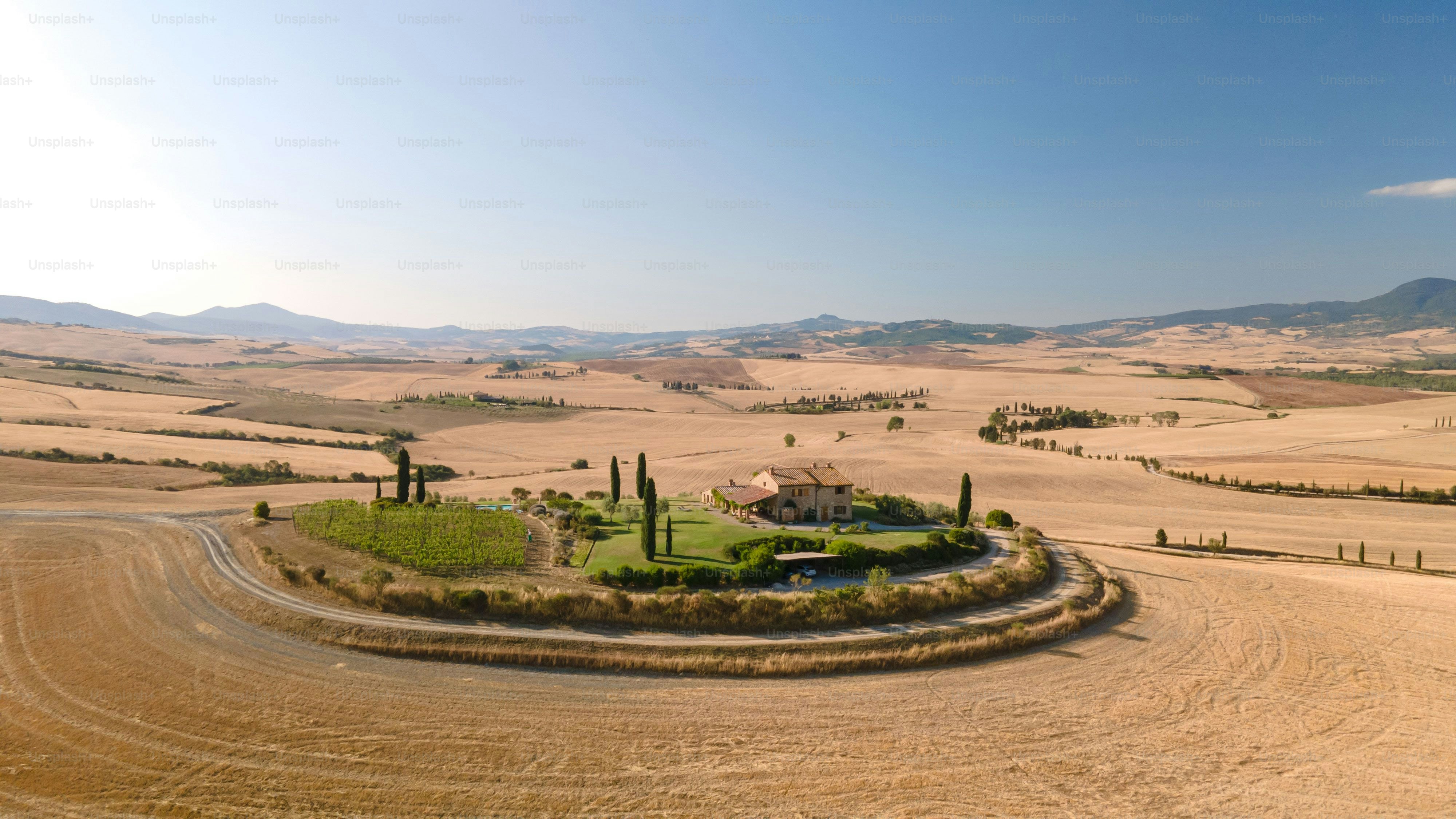 An aerial view of a round green area in Val d'Orcia with a blue sky in the background, Tuscany, Italy
