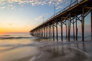 A low angle shot of a beach pier under the bright sunset in Carolina Beach, North Carolina