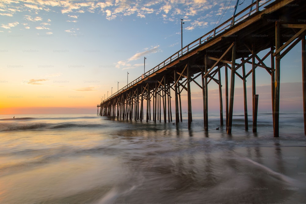 A low angle shot of a beach pier under the bright sunset in Carolina Beach, North Carolina