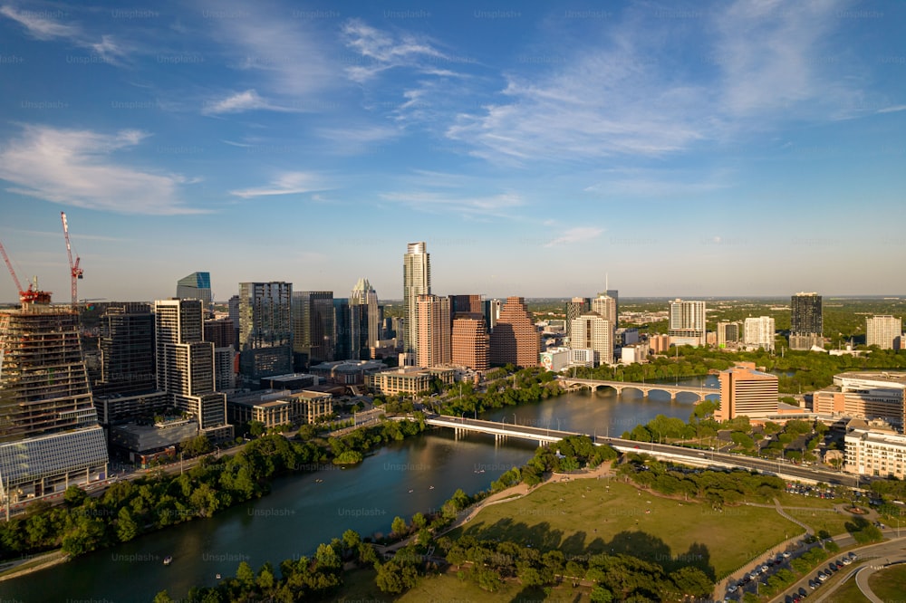 A drone shot of TX skyline with waterfront, greenery and blue cloudy sky in Austin city