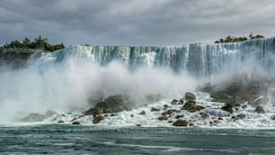 Una hermosa vista de las cataratas del Niágara y la neblina de agua, y la costa rocosa del río Niágara, en un día nublado