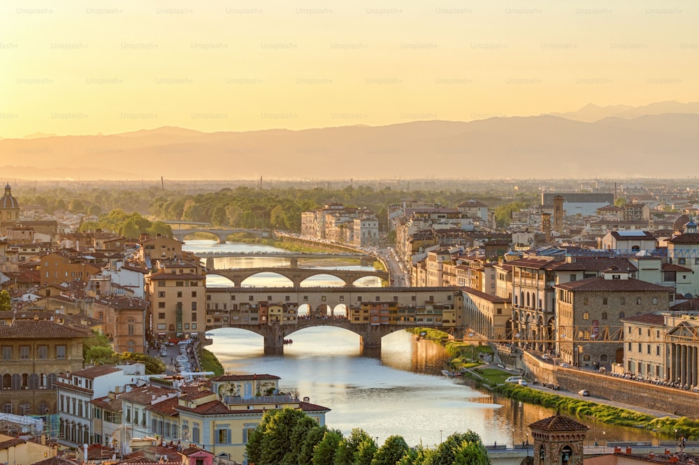 A scenic view of the Ponte Vecchio bridge at the river Arno in Florence at sunset