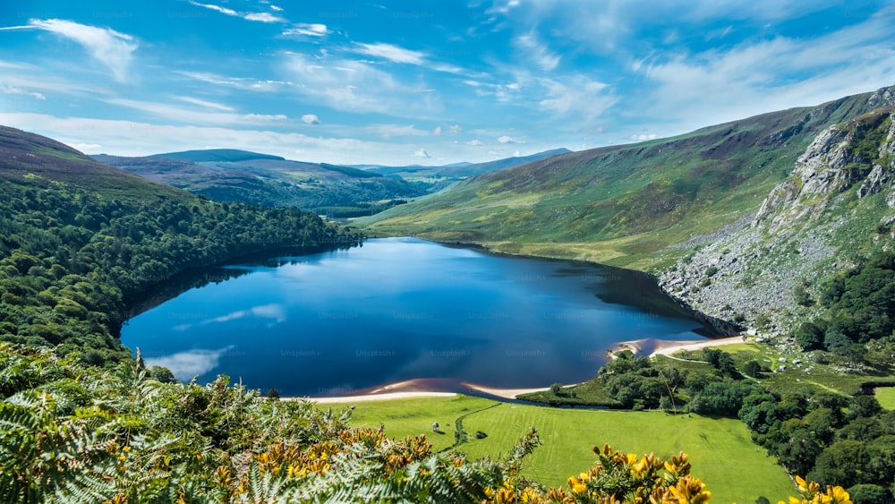 An aerial view of a calm lake surrounded by greenery-covered hills in Wicklow county town of Ireland
