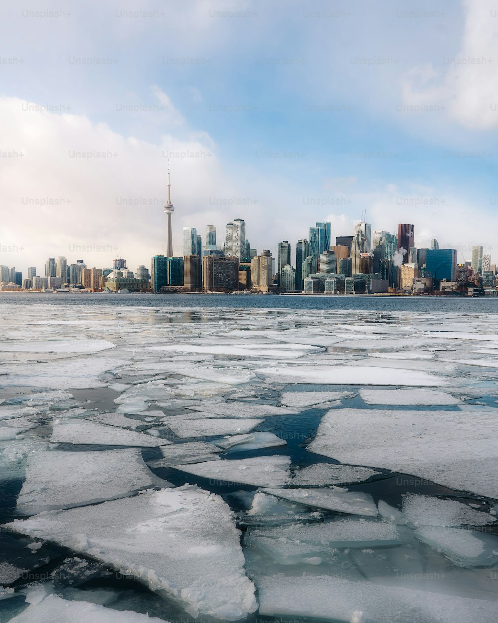 A vertical shot of the frozen river with tall buildings of Toronto in the background, Canada