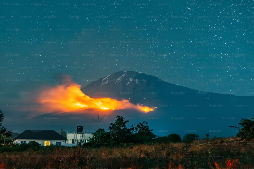 A landscape of Mount Kilimanjaro on fire on green wood in Tanzania with a foggy blue sky