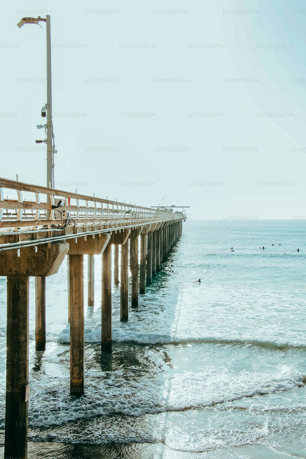 A vertical shot of the La Jolla pier on the ocean with a cloudless sky background in San Diego