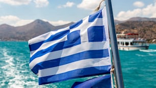 Una bandiera della Grecia che sventola su una nave al largo delle coste greche