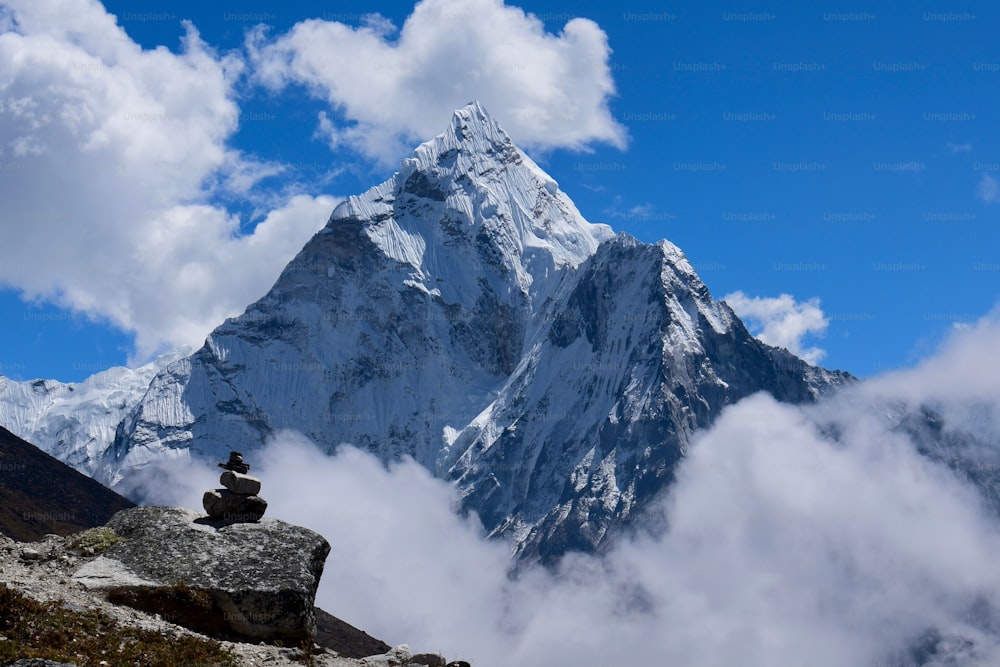 Eine schöne Aufnahme des Mount Everest, umgeben von Wolken und einem Felsblock im Vordergrund