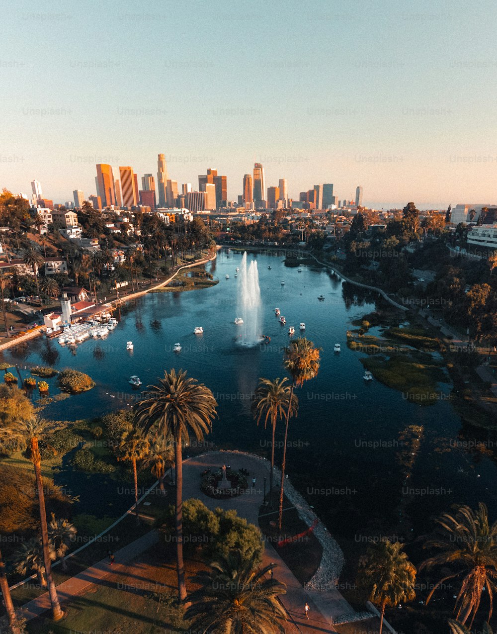 A vertical shot of a lake surrounded by skyscrapers under the sunlight in Los Angeles, California