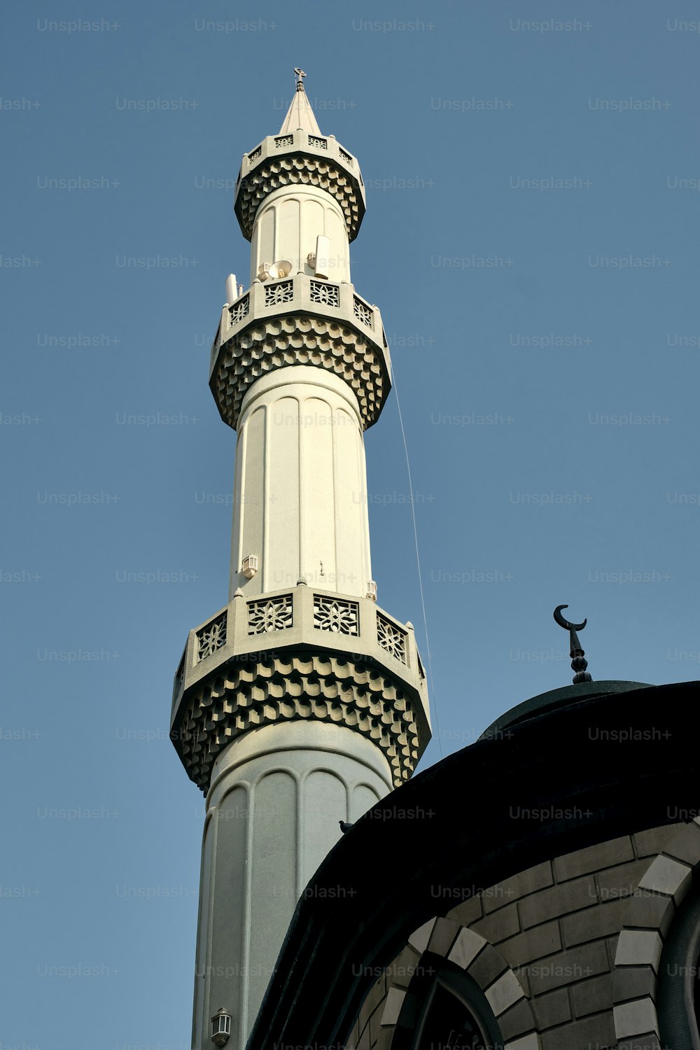A low-angle shot of a minaret of a mosque against a blue sky on a sunny day in Dubai