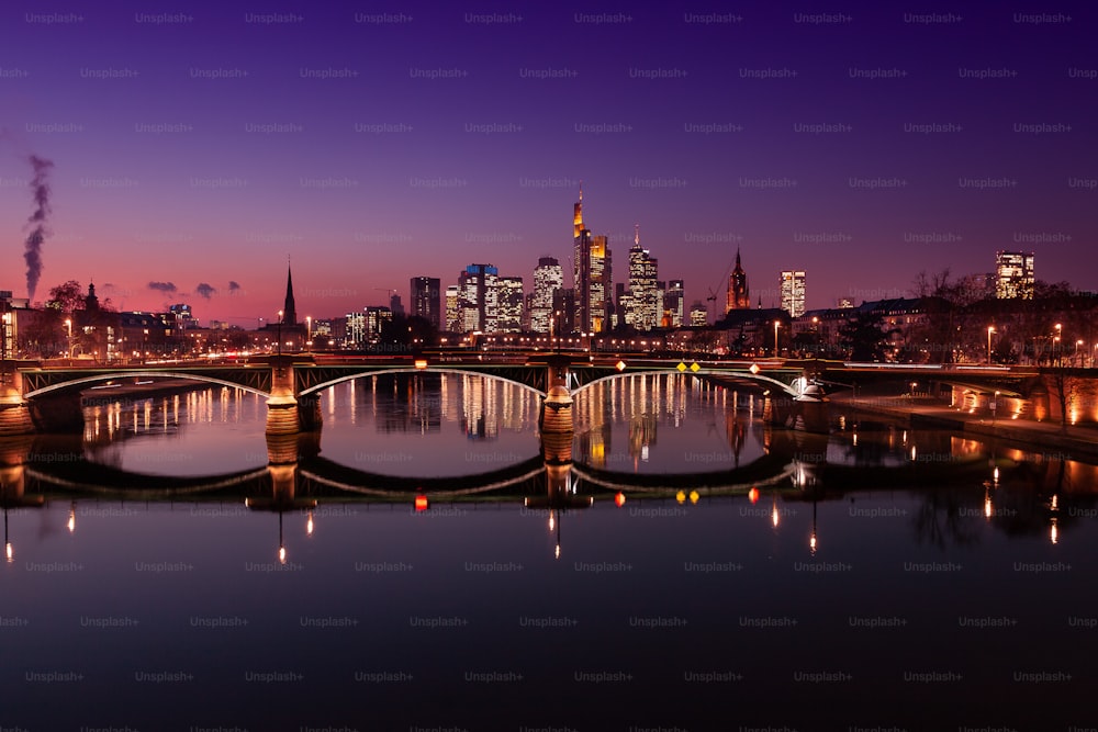 Frankfurter Skyline in der blauen Stunde. Gebäude beleuchtet. Im Vordergrund die Floßbrücke.