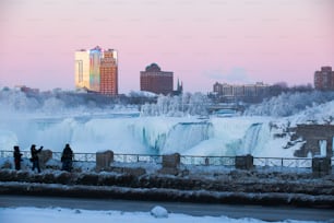 Eine Gruppe von Touristen genießt die herrliche Aussicht und macht Fotos an den Niagarafällen während eines rosa Sonnenuntergangs