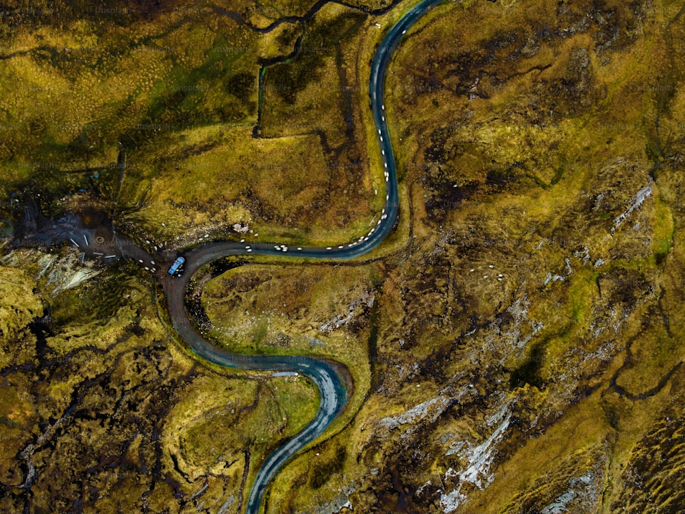 Une vue aérienne d’une rivière sinueuse coulant à travers un paysage verdoyant avec un éventail de rochers, d’arbres et d’autres végétaux