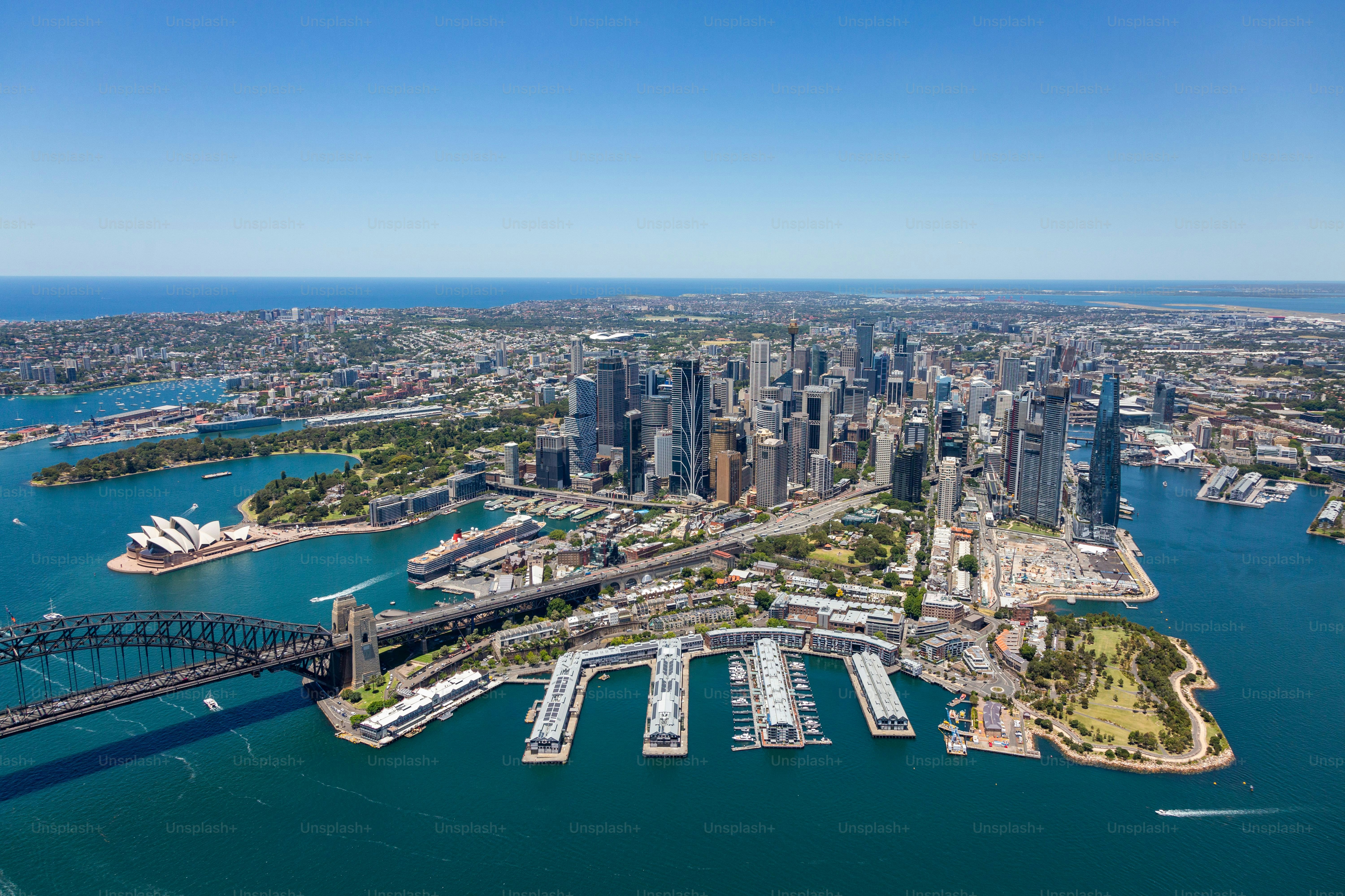 An aerial view of the beautiful Sydney, Australia skyline and its harbor, featuring boats peacefully sailing in the waters