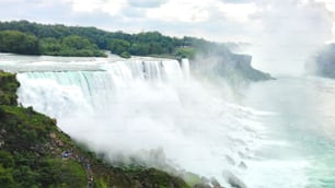 A majestic view of Niagara Falls with people enjoying it by walking along its side