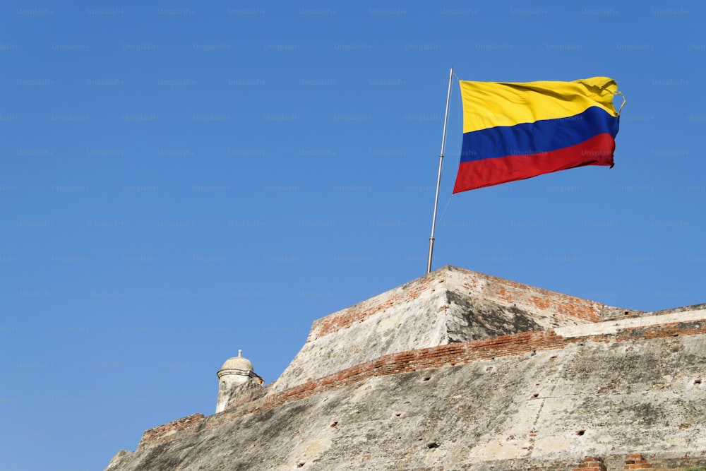 Eine kolumbianische Flagge weht im Wind über die verwitterten Mauern der Festung Castillo San Felipe de Barajas in Cartagena de Indias, Kolumbien.
