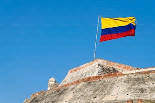 A Colombian flag is streaming in the wind over the weathered walls of the fortress of Castillo San Felipe de Barajas in Cartagena de Indias, Colombia.