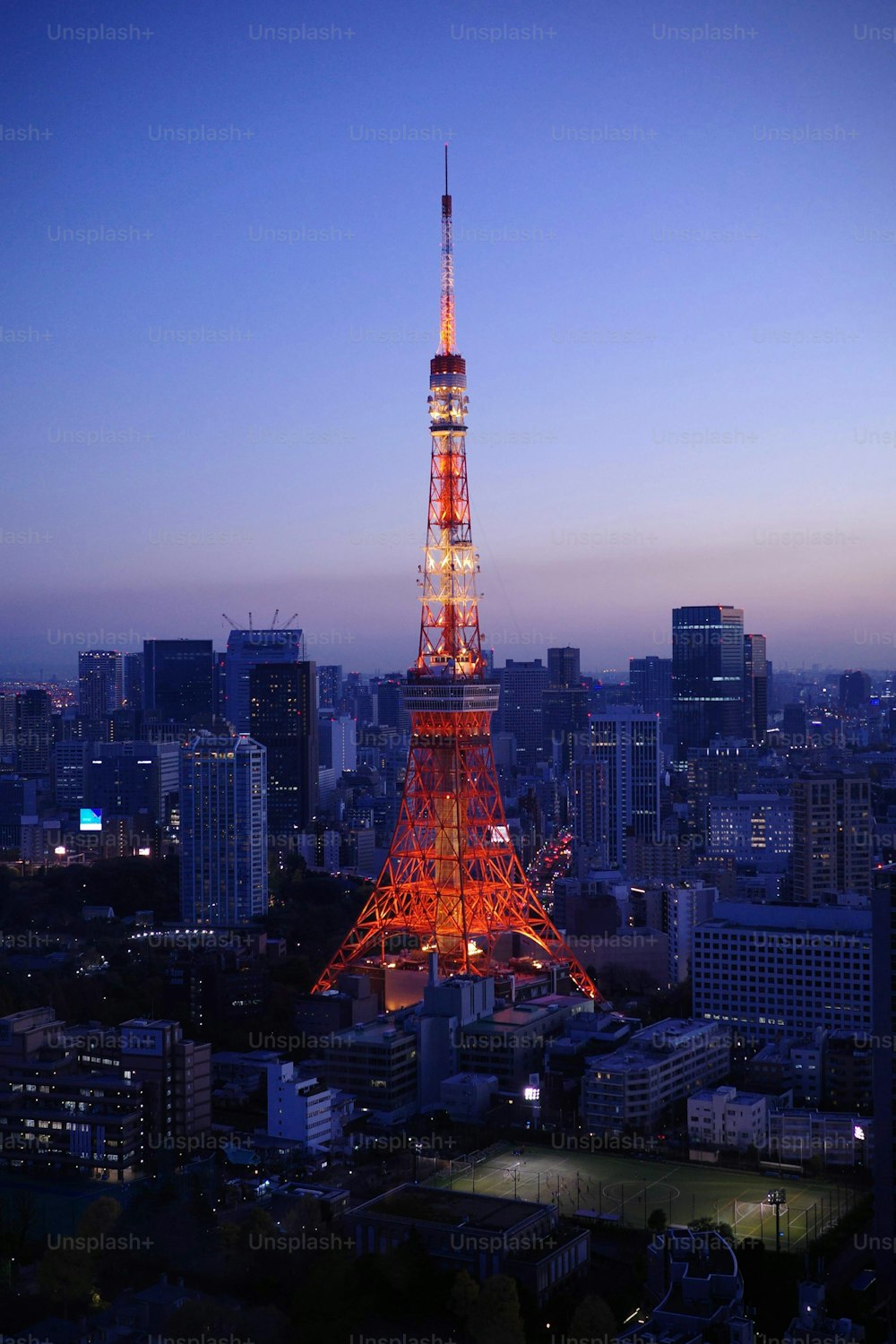 Questa suggestiva immagine dell'iconica Torre rossa di Tokyo illuminata contro il cielo blu è perfetta per il tuo prossimo progetto fotografico stock