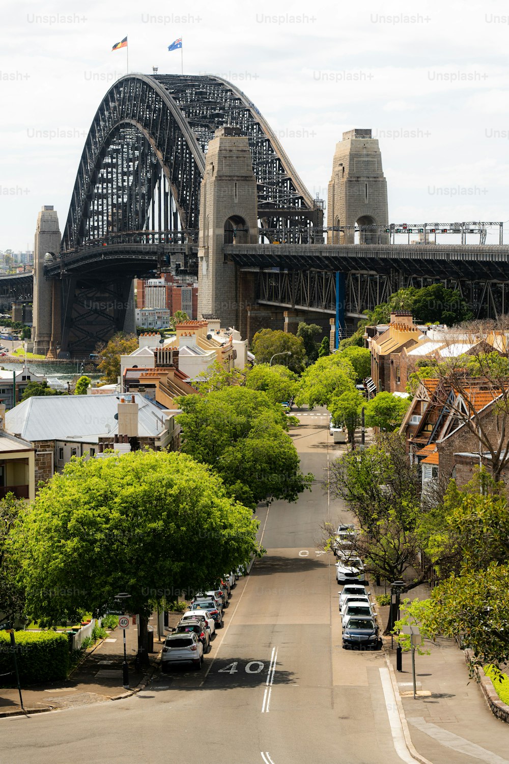A vertical view of buildings before the Sydney Harbour bridge on a cloudy day