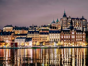 스웨덴 스톡홀름의 저녁에 고요한 물가에 조명이 켜진 건물들이 줄지어 서 있습니다