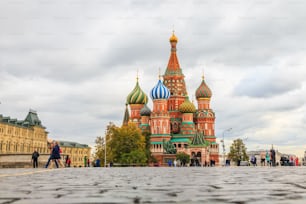 A group of diverse people make their way along the cobblestone streets of Moscow, passing by the iconic Saint Basil's Cathedral and a nearby building