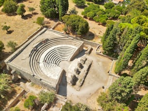 Uma vista aérea do histórico teatro Odeon em Kos, Grécia, cercado por uma exuberante floresta de árvores
