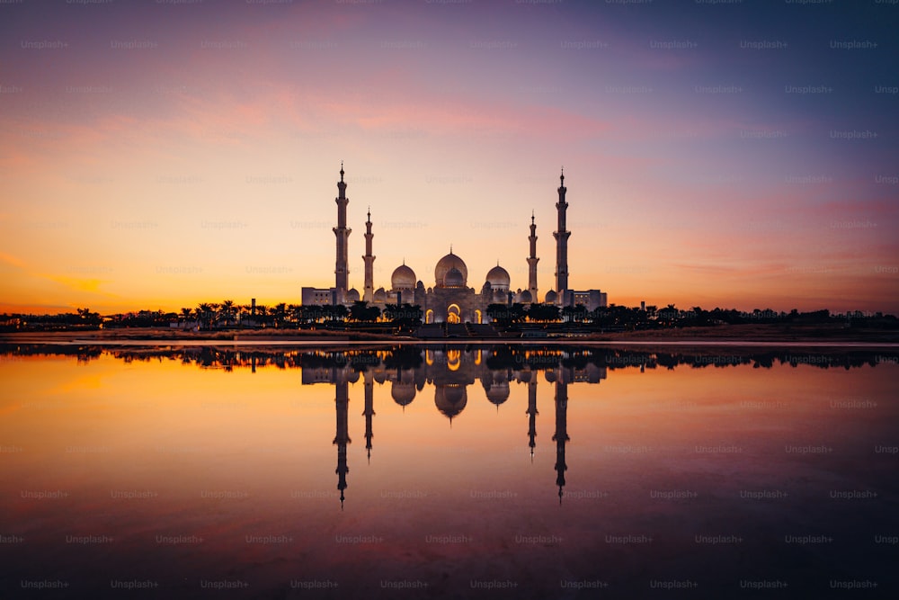 This the Sheikh Zayed Mosque at sunset with its reflection on water