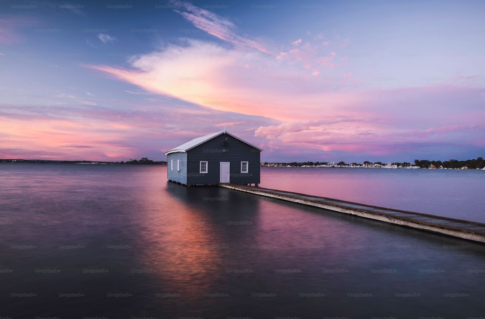 Panoramic view of the Perth skyline from a boat house as the sun sets, with a rosy pink hue illuminating the sky