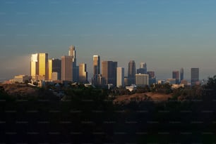 A vibrant city skyline featuring multiple towering skyscrapers illuminated by the setting sun