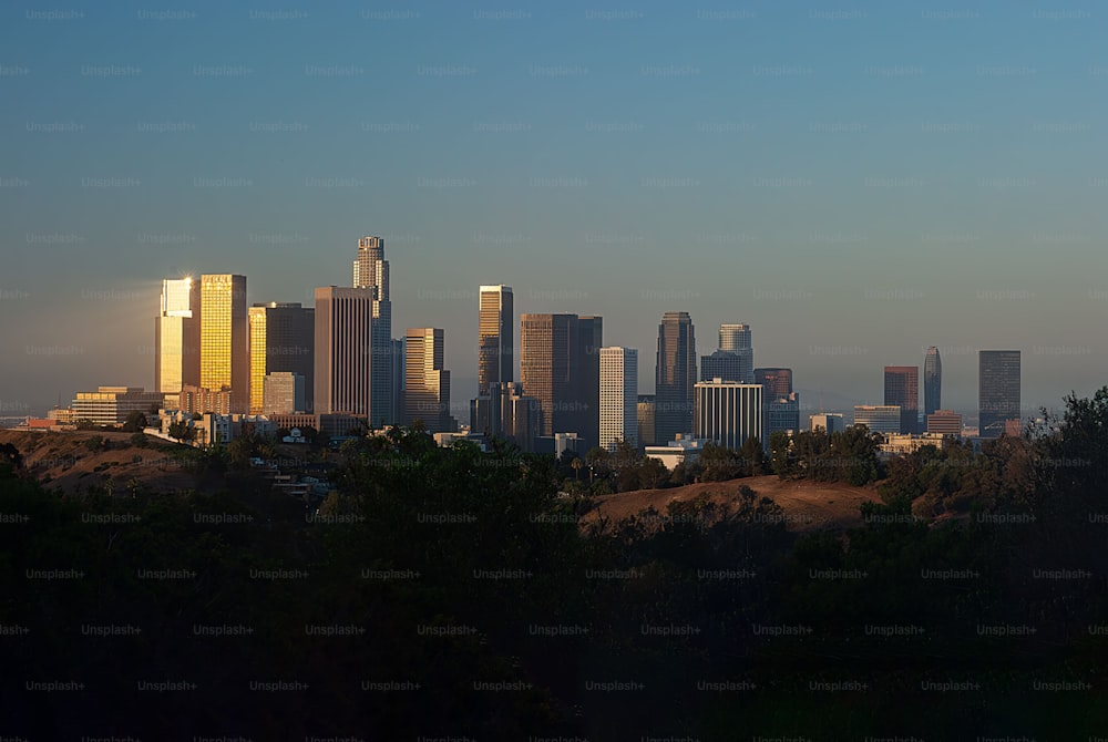 A vibrant city skyline featuring multiple towering skyscrapers illuminated by the setting sun