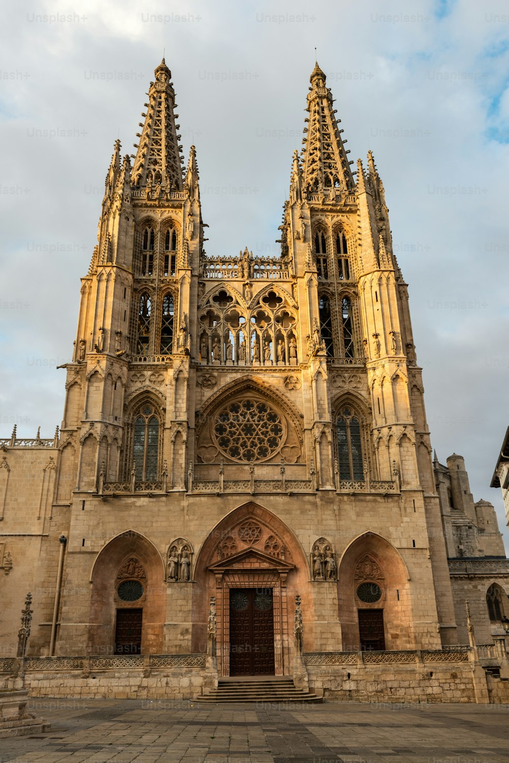 Side view of the two western Flamboyant spires of the Gothic Roman Catholic cathedral in Burgos (1221-1567) illuminated by the setting sun, Spain.
